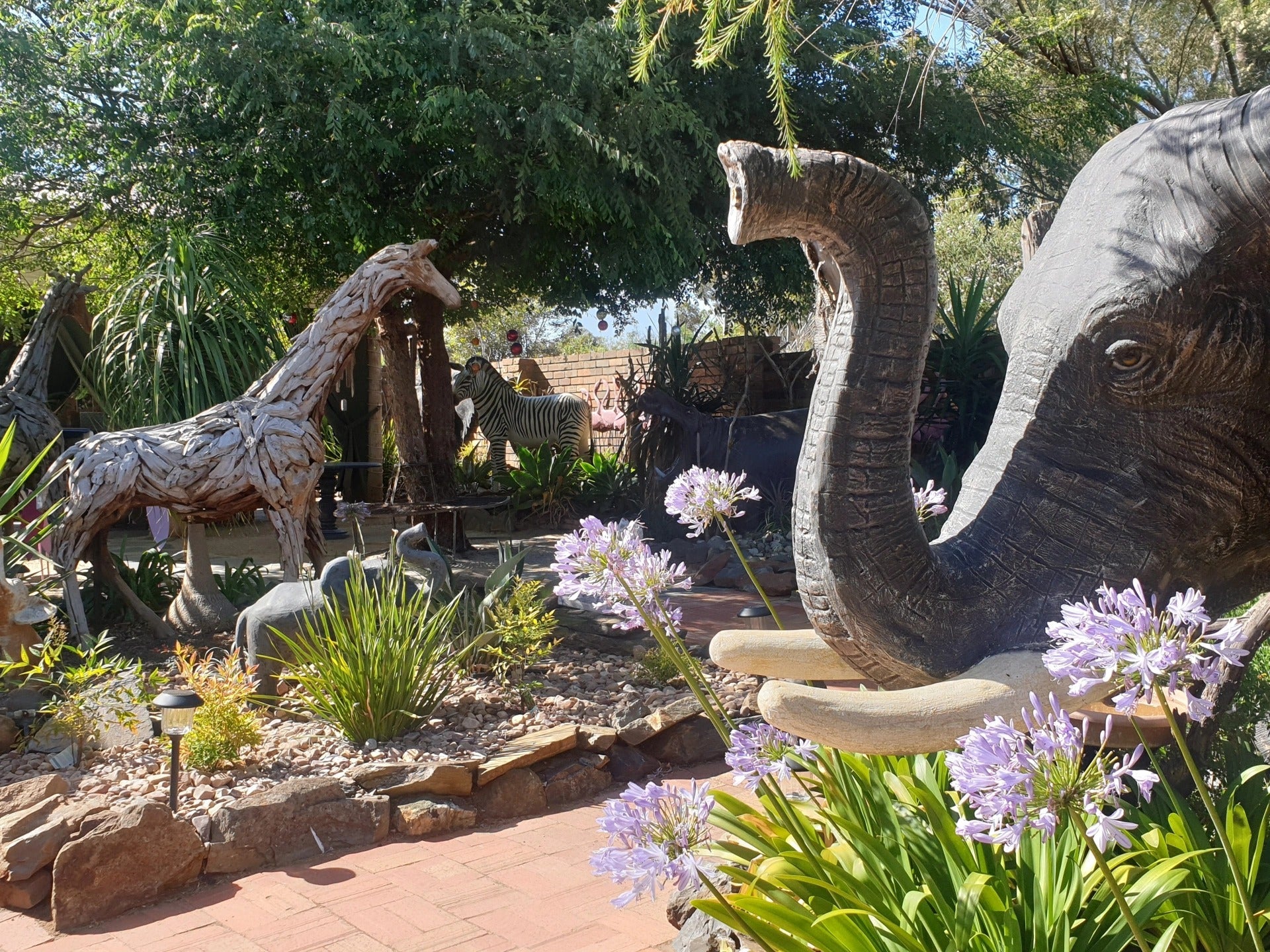 Driftwood animal sculptures among agapanthus at Elephants Rest, Callington